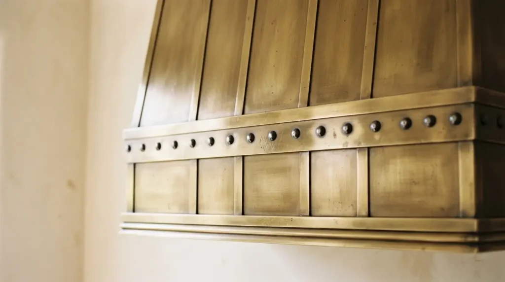 Close-up of a range hood with horizontal riveted metal banding trim
