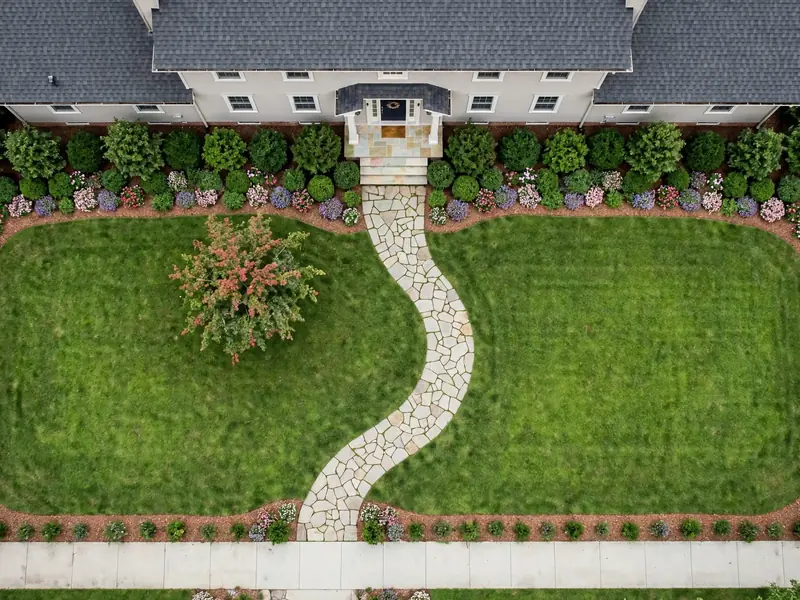 Overhead front yard landscape layout showing a house entrance, curved walkway, lawn, shrubs, and planting beds.