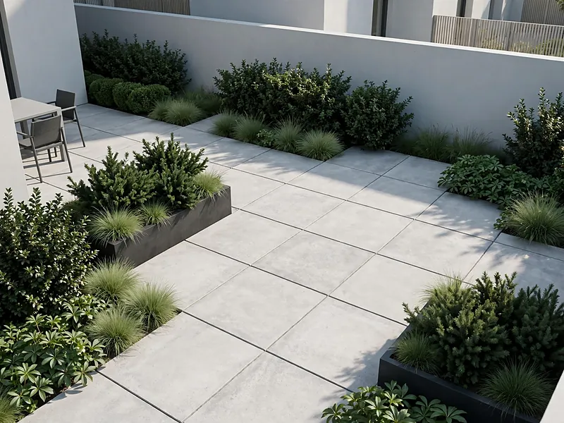 Modern garden with pale gray paving, green evergreen shrubs, and dark contemporary planters.