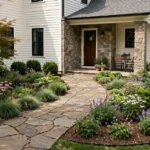 Attractive suburban home with landscaped front yard, stone walkway, flowering plants, shrubs, and outdoor seating.