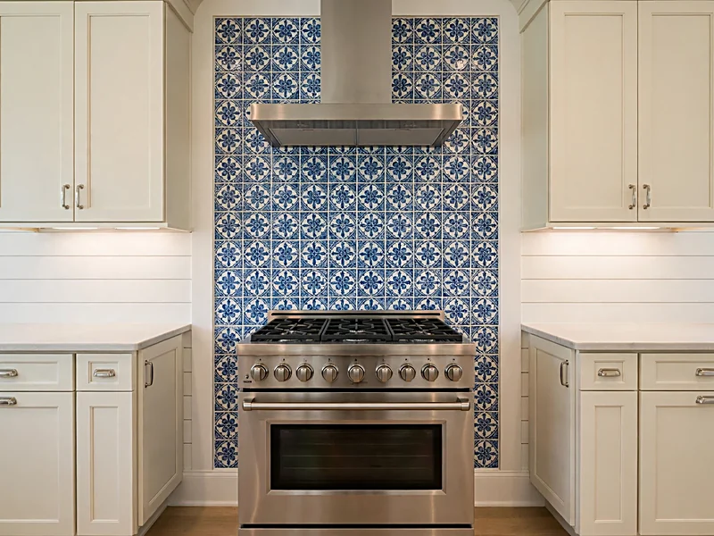 Kitchen range with blue patterned ceramic tile behind the stove and white shiplap on adjoining walls.
